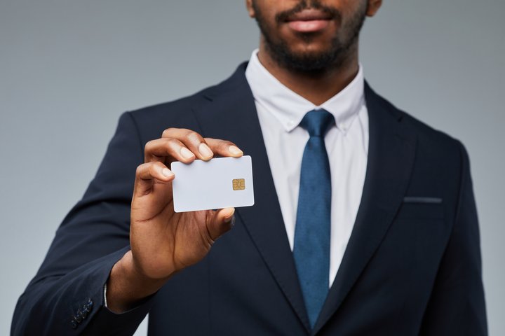 Close up of black businessman holding blank business credit cards personally guaranteed mockup and showing to camera, copy space